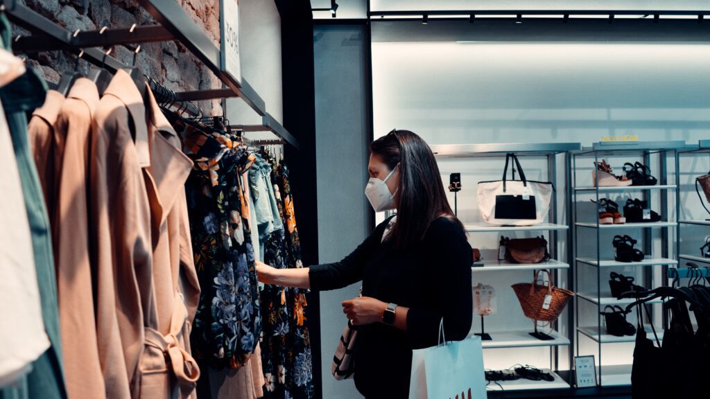 Image of a woman clothes shopping with a mask on.